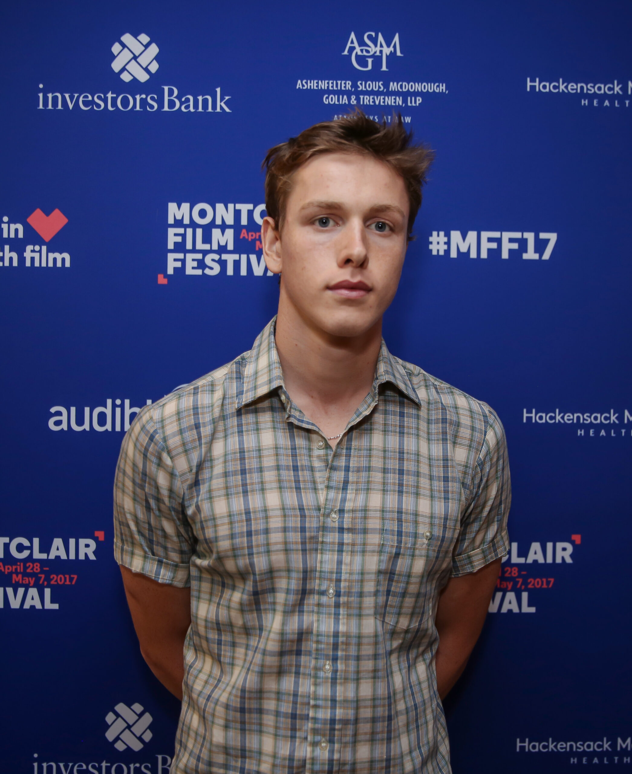 Harris Dickinson posando en photocall durante un festival de cine, fondo azul con logotipos